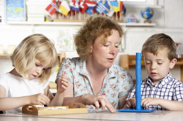 Adult Helping Two Young Children at Montessori/Pre-School