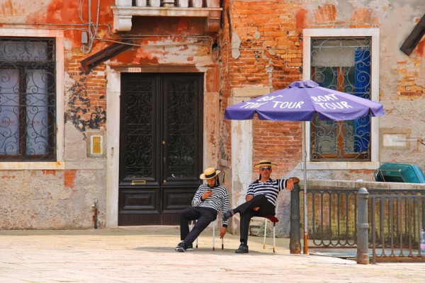 Two gondoliers on the docks awaiting tourists in Venice, Italy