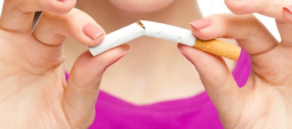 Young woman is breaking a cigarette, quit smoking concept, isolated over white