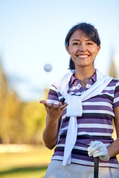 Beautiful female golf player playing with the ball