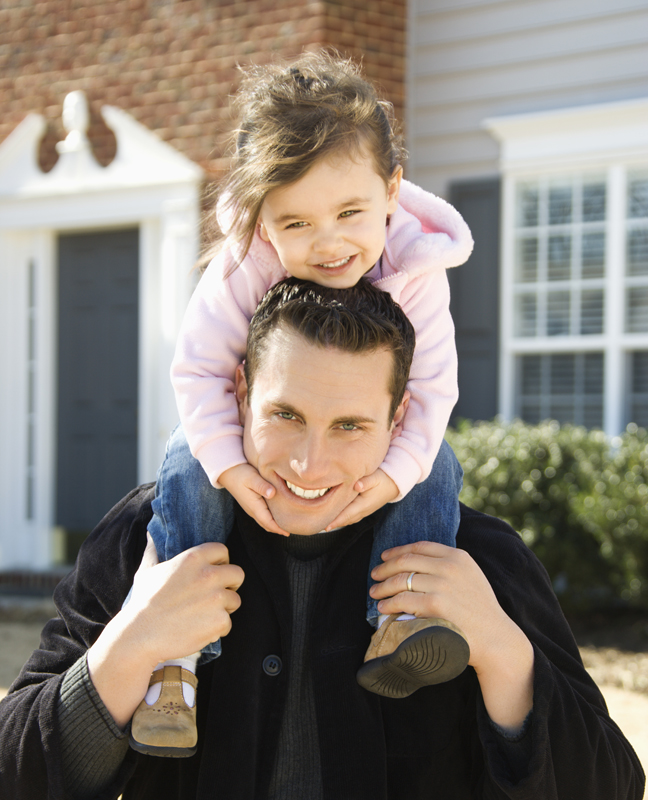 Caucasian father carrying daughter on shoulders.