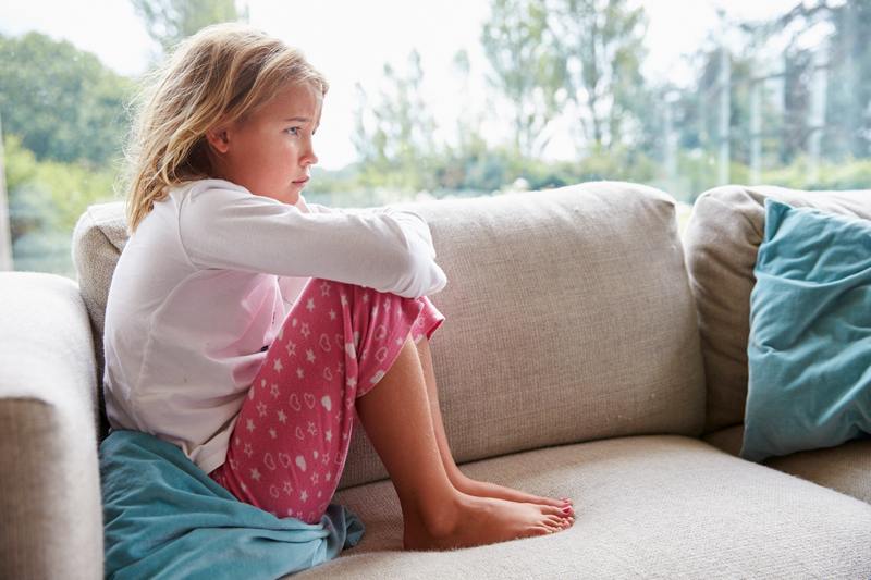 Unhappy Young Girl Sitting On Sofa At Home