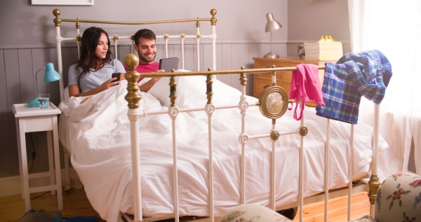 Young Couple In Bed Using Digital Tablet And Mobile Phone
