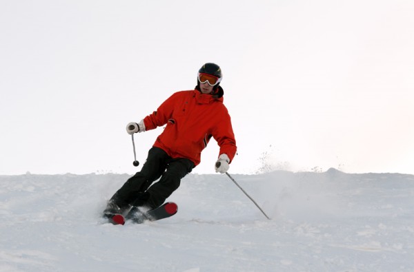 Man skiing in the orange jacket on the mountain