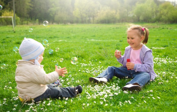 Two children are sitting on green meadow