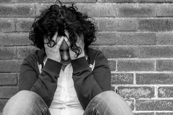 Young hopeless woman sitting against wall