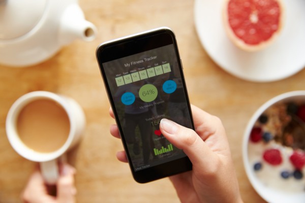 Person At Breakfast Looking At Fitness App On Mobile Phone