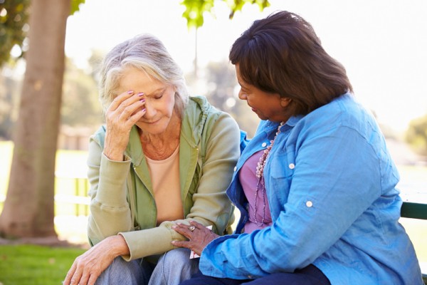 Woman Comforting Unhappy Senior Friend Outdoors