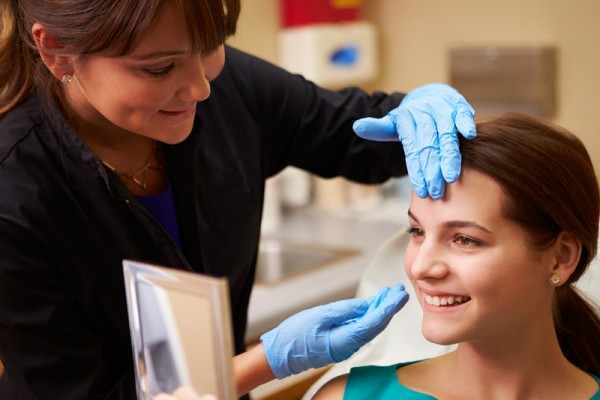 Female Client Looking In Mirror After Botox Treatment